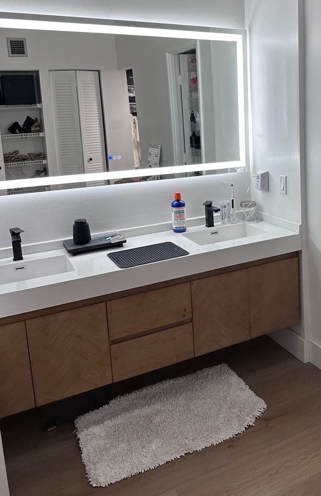 A double vanity with two sinks under a backlit mirror